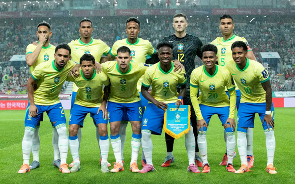 Brazilian national soccer team poses for a group photo in yellow-green kits before a packed stadium.