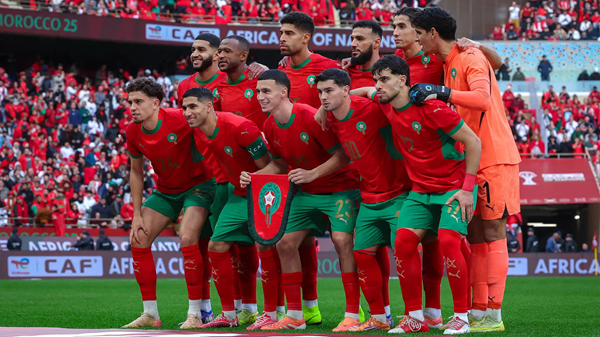 Morocco national football team huddles together on the pitch in red and green kits before kickoff.
