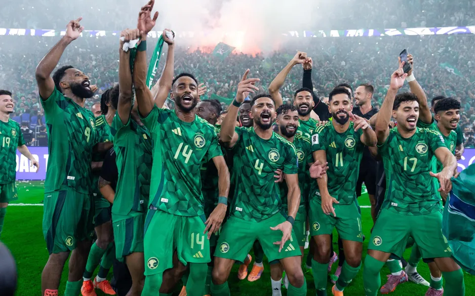 Celebrating soccer team in green uniforms cheering on stadium field with smoke and confetti. Saudi Arabia