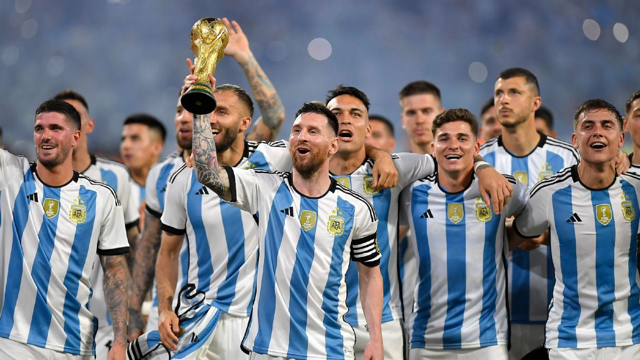 Argentinian soccer players in striped jerseys celebrate, lifting a golden trophy above their heads.