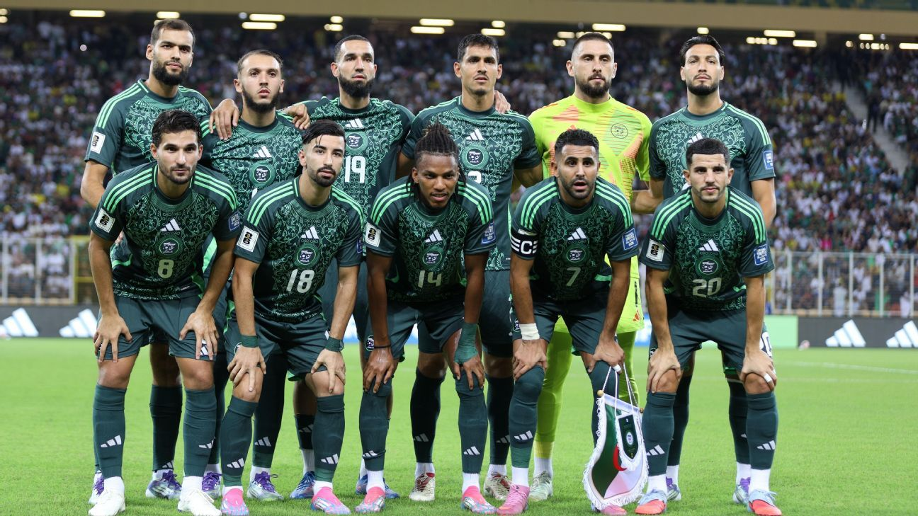 Algeria soccer team poses for a group photo in green kits inside a packed stadium.
