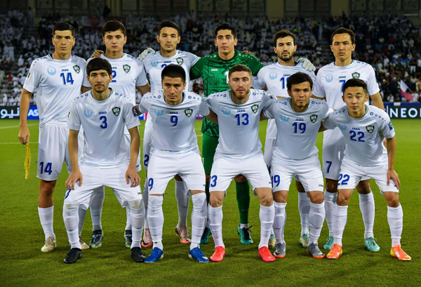 Soccer team lineup posing on field in white and green uniforms before a match. Uzbekistan