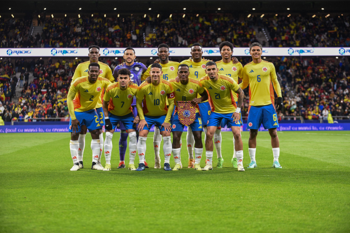 Colombian national soccer team poses together on the field in yellow kits before a match.